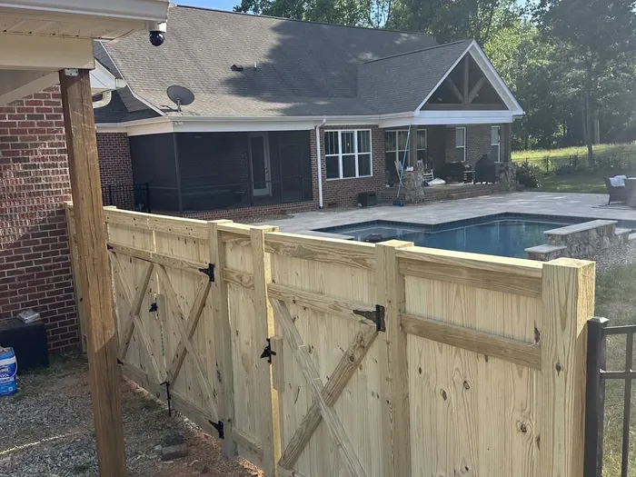A row of fence posts set in concrete along a strung line, the rails not yet hung, no people